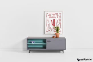 Grijze laagkast met turquoise binnenwerk, open vakken en schuifdeur. Daarop potplant en decoratie. Boven abstract wandkunstwe