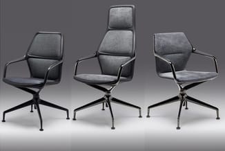 Drie grijze designstoelen met armsteunen en zwart metalen onderstel op wielen, getoond uit verschillende hoeken tegen grijze
