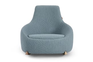 Grijsblauwe fauteuil met gequilteerde stof, houten poten, modern design, frontaanzicht op witte achtergrond.