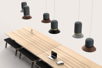 Houten vergadertafel met zwarte bankjes, laptop en documenten, omgeven door zwart-grijze hangende akoestische panelen met bru