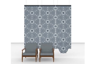 Akoestisch scheidingspaneel met geometrisch patroon in grijs, achter twee houten fauteuils met grijze bekleding.
