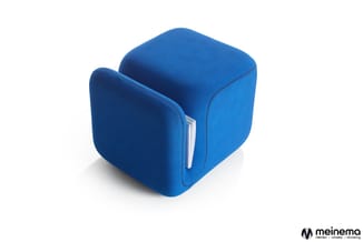 Blauwe kubusvormige poef of zitblok met textielstructuur, voorzien van een witte kaarthouder aan de zijkant.