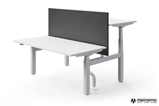 Elektrisch verstelbaar bureau met wit blad, grijze onderstel, zwarte akoestische scherm en ergonomische zithouding.