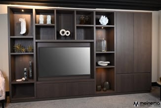 Donkerbruine tv-kast met open vakken, gesloten deuren en ingebouwde tv-scherm in moderne woonkamer met decoratieve objecten.