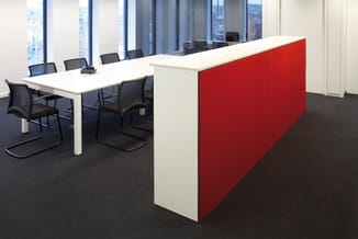 Moderne vergaderruimte met witte rechthoekige vergadertafel, zwarte bureaustoelen, rood-wit gestructureerde scheidingswand en