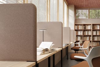 Moderne studieruimte met beige akoestische scheidingswanden, houten werkblad, witte bureaustoelen met bruine zitting, leeslam