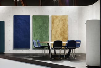 Moderne vergaderruimte met ronde tafel, zwarte stoelen met blauwe accenten, drie gekleurde wandpanelen (blauw, groen, geel) o