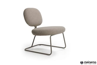 Grijze loungestoel met ronde rugsteun en zitting op metalen sledepoten, vrijstaand tegen witte achtergrond. Meinema-logo onde