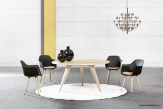 Ronde houten tafel met naturel finish, vier zwarte stoelen met houten poten, witte ronde vloerkleed, grijze betonvloer, gele