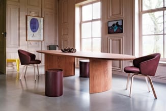 Moderne vergaderruimte met ovale houten tafel, paarse stoelen, houten podia en grote ramen in klassiek interieur.