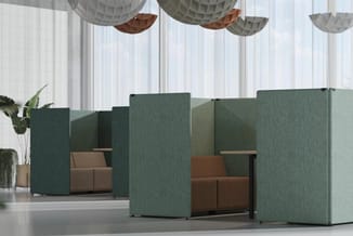 Groene akoestische zitboxen met bruine kussens in open kantoorruimte met witte gordijnen en hangende decoratieve elementen.
