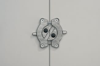 Metalen deurkruk in geborsteld staal op houten deur, zilverkleurig met twee zwarte bolletjes en schroeven zichtbaar.