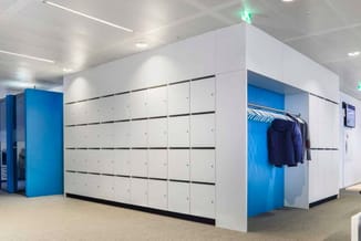 Modulaire witte kastenwand met blauwe accenten en zwarte horizontale lijnen in moderne kantoorruimte met betonvloer.