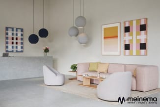 Kantoorinrichting met roze hoekbank, witte fauteuils, hangende grijze bollen, grafische wandkunst en receptiebalie in grijze