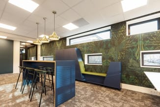 Modern kantoor met blauwe akoestische schermen, geel zitkussen, barstoel met zwarte frame, goudkleurige hanglamp, botanisch b