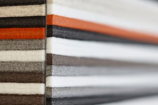 Stapel stoffen stalen in verschillende kleuren: donkerbruin, beige, oranje en grijs, weergegeven als meubelstofmonsterset.
