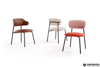 Vier moderne stoelen met zwart metalen frame in verschillende kleuren: bruin leer, beige stof, roze stof en oranje stof. Mein