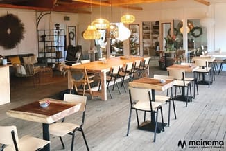 Modern kantoor met houten tafels, beige/witte stoelen, gouden hangende lampen, houten balken, lounge-area en glazen deuren.