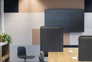 Moderne kantoorinrichting met grijze akoestische panelen, zwarte televisie, houten bureau, grijze draaistoelen en zwarte bure