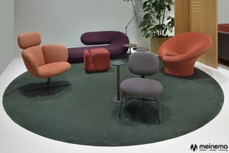 Moderne loungeset op groen rond tapijt: terracotta stoelen, paarse sofa, rode poef, grijze kruk, hoge tafel, potplanten en ho