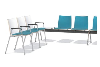 Wachtruimte met tafel en stoelen: drie witte stoelen met turquoise zitting links, drie turquoise stoelen rechts, zwarte tafel
