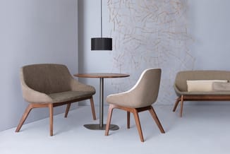 Lounge-opstelling met grijsbruine stoelen met houten poten, ronde tafel en hangende zwarte lamp in modern kantoor.