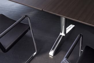 Overzicht van kantoormeubels: zwarte bureaustoel met chromen armsteunen, donker houten tafel en grijze stoel op donkere vloer