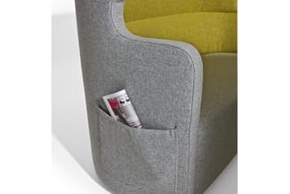 Grijze fauteuil met gele achterwand, voorzien van een zijvak met een brochure erin.
