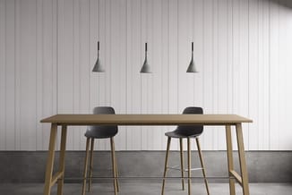 Houten vergadertafel met zwarte barkrukken in minimalistisch kantoor met witte wanden en grijze betonvloer.