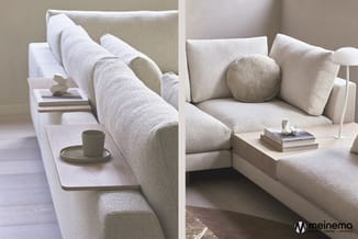 Beige/crème loungebank met armleuningen en kussens in minimalistisch interieur, toegangstafel met kopje en boeken.