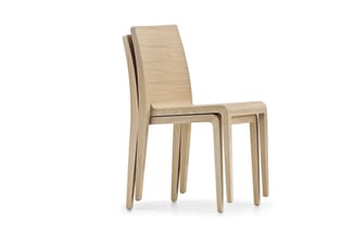 Houten stoelen in natuurlijke houtkleur, gestapeld op elkaar. Minimalistisch design met rechte rugleuning en vier slanke pote