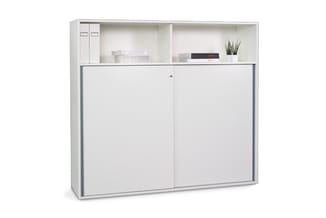 Witte kastenwand met bovenkasten en twee schuifdeuren, gevuld met ordners, dozen en plantje.
