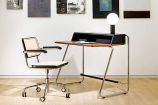 Moderne werkplek met houten bureau met zwarte bovenkant, stalen frame en bureaulamp. Witte bureaustoel met zwarte armleuninge