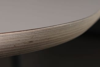 Detailopname van een houten tafelblad met duidelijk zichtbare houtnerf, donkerbruine kleur en afgeronde rand.
