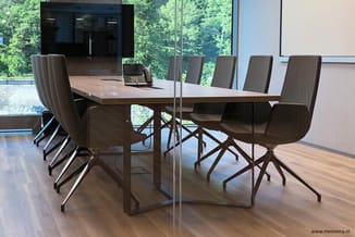 Moderne vergaderkamer met houten tafel, grijze stoelen met wieltjes, glazen wand, zwarte keukenkasten en panoramisch uitzicht