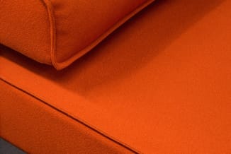 Oranje gestoffeerde bank met textielkwaliteit, detail van zitting en ruggedeelte met naden zichtbaar.