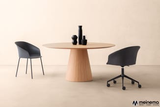 Ronde houten vergadertafel met kegelvoet en zwarte decoratieve objecten, geflankeerd door twee zwarte stoelen in een minimali