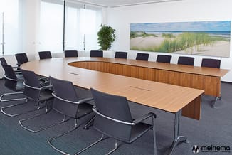 Moderne vergaderruimte met houten vergadertafel, zwarte buisstoel en strandlandschapkunstwerk aan wand.
