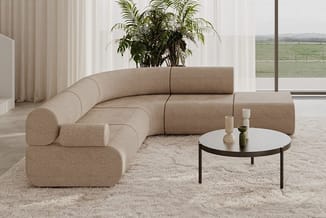 Beige modulaire zitgroep in ronde vorm met ronde salontafel, in lichte kantoorruimte met raam en plant.