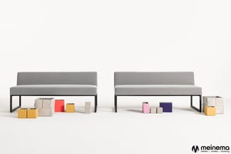 Twee grijze banken met zwart metalen frame, onder elkaar verschillende gekleurde opbergboxen in beige, rood, geel en paars.