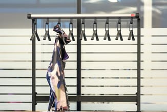 Garderoberek met zwart metalen frame en aluminium bovenbuis, neun haaken met een uitgehangen sjaal in paarse en blauwe tinten