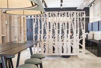 Moderne kantoorrui met wit opengewerkt scheidingspaneel met boompatroon, zwarte werktafel, groene stoelen, houten kasten en h