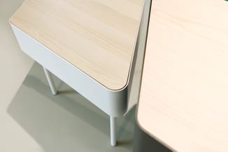 Moderne vergadertafel met licht houtfineer blad en wit onderstel met grijze poten, gedeeltelijk zichtbaar vanuit bovenaanzich