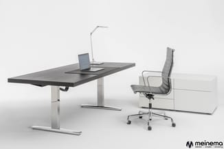 Moderne kantoorwerkplek met zwart bureau op wit onderstel, grijze bureaustoel met wielen, bureaulamp en laptop. Witte kastenw