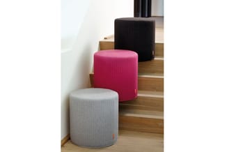 Drie ronde poefs in grijs, roze en zwart met geribbeld textieloppervlak, opstelling op houten trap.
