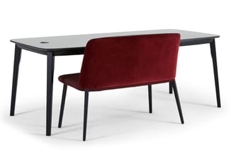 Zwart bureau met grijsblad en rode fluwelen stoel met zwarte poten in kantooropstelling.