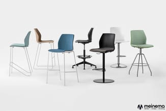 Collectie vergaderstoelen in verschillende kleuren en ontwerpen: blauw, groen, wit, zwart en bruin op metalen poten, tegen ne