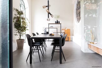 Moderne vergaderruimte met zwarte rechthoekige tafel, zwarte stoelen, potplant, hangende verlichting, wandkasten en grote ram