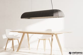 Donkergrijze hanglamp boven houten eettafel met witte stoelen in minimalistisch interieur.