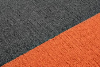 Twee tapijttegels in grijs en oranje, diagonaal tegen elkaar geplaatst, toont kleur- en materiaalkeuze.